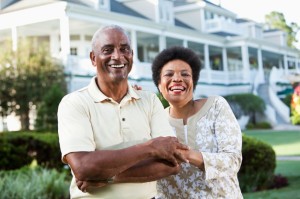 Picture of mature African American couple (50s and 60s) at a country club, standing in front of clubhouse. Main focus on woman.
