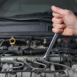 Man using a wrench in a car engine repair project.