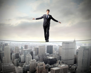 A man balances on a tight rope over a city skyline.