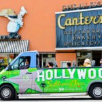A picture of Los Angeles's Famous Canter's Deli Bakery and Restaurant, with a Hollywood sightseeing tour bus with tourists passing nearby.