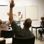 Picture of adult education class raising hands to ask questions.