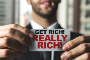 Picture for spotting investment scams post, which shows a man holding a get really rich sticker