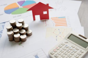 Real estate professional audit blog post image showing coins, a calculator, and a toy house.